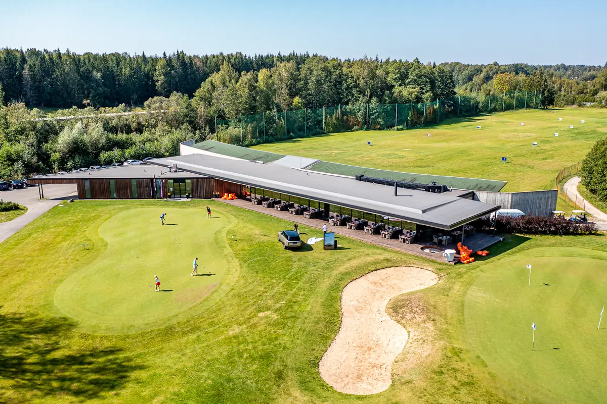 The V Golf Club clubhouse and driving range with the practice green in the foreground